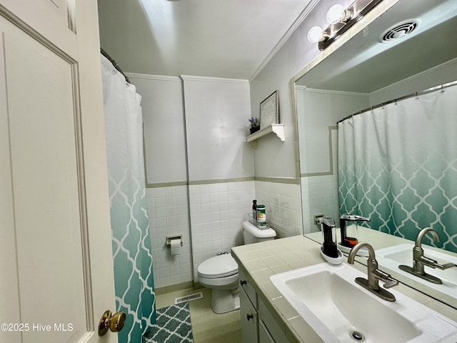 bathroom featuring tile walls, vanity, toilet, crown molding, and tile patterned floors