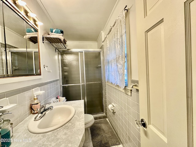 bathroom featuring a shower with shower door, tile walls, ornamental molding, vanity, and toilet