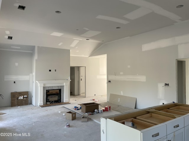 unfurnished living room with a tiled fireplace and lofted ceiling