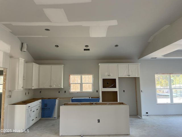 kitchen with vaulted ceiling, white cabinets, and a kitchen island