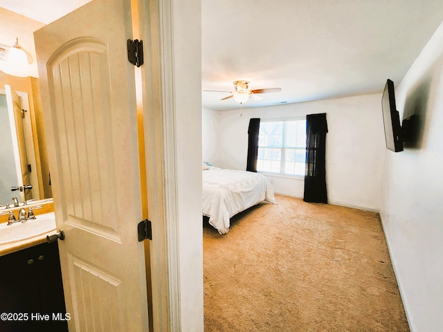 carpeted bedroom with ceiling fan and sink