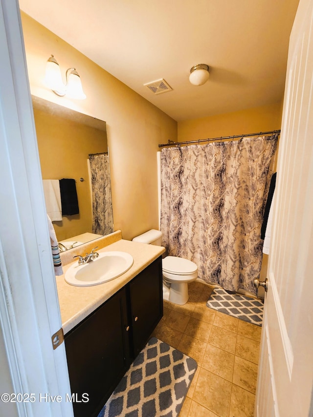 bathroom with toilet, vanity, and tile patterned flooring