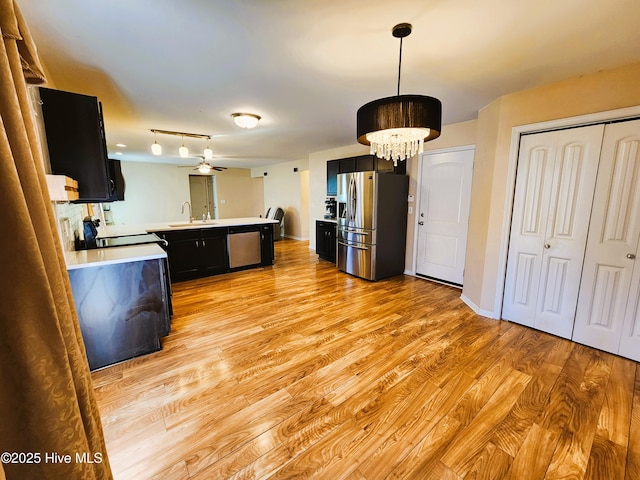 kitchen with stainless steel appliances, light hardwood / wood-style floors, ceiling fan, and pendant lighting