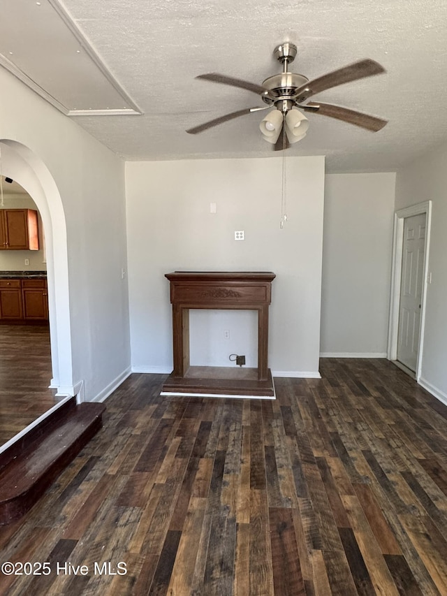 interior space featuring ceiling fan, dark wood-type flooring, and a textured ceiling