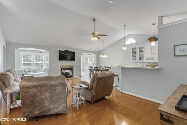 living room with ceiling fan, a multi sided fireplace, wood-type flooring, and vaulted ceiling