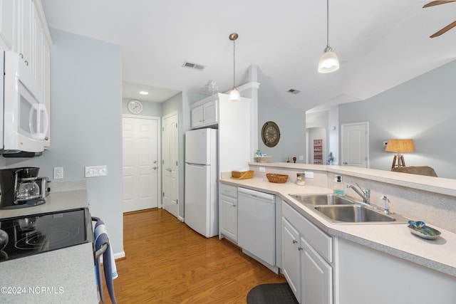 kitchen with sink, white appliances, white cabinetry, hanging light fixtures, and light wood-type flooring