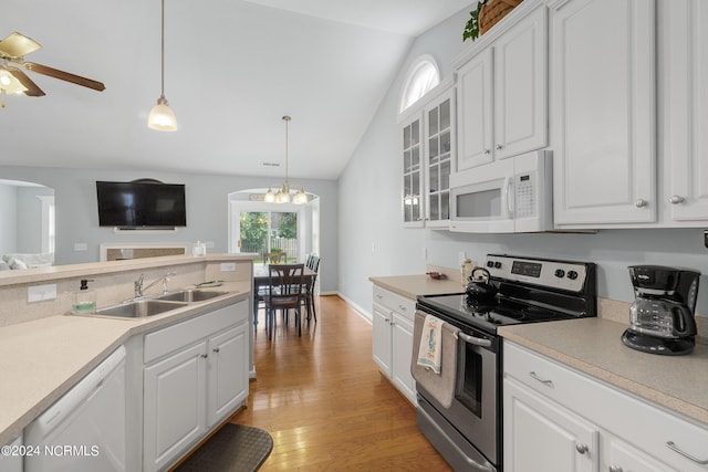 kitchen featuring lofted ceiling, sink, white appliances, white cabinets, and decorative light fixtures