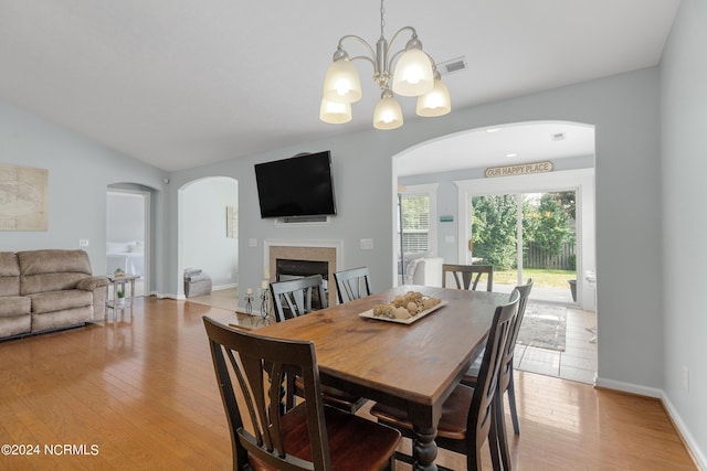 dining area featuring vaulted ceiling, a notable chandelier, and light hardwood / wood-style floors