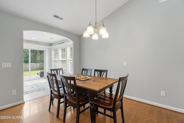 dining room with a notable chandelier, vaulted ceiling, and light wood-type flooring