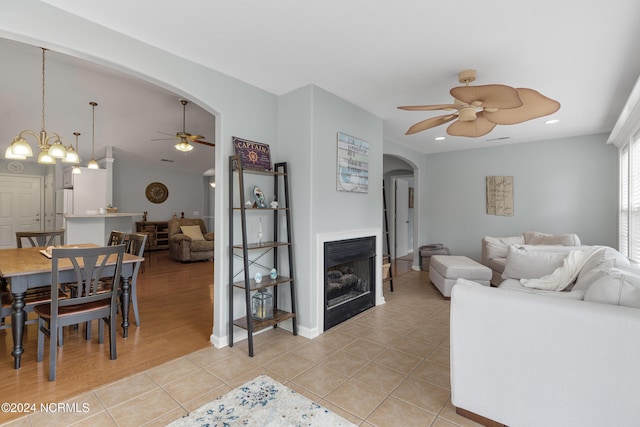 living room featuring ceiling fan with notable chandelier and light tile patterned floors