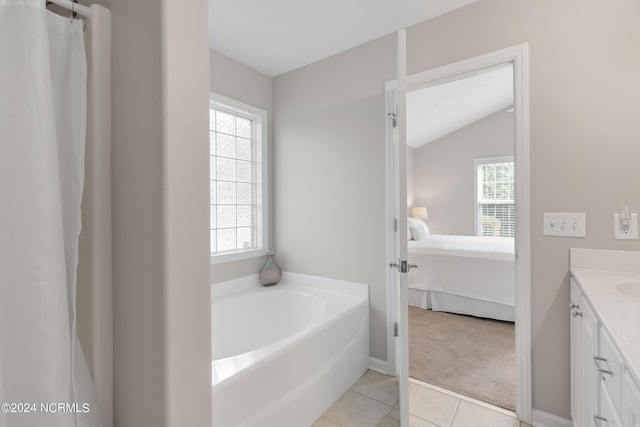 bathroom featuring tile patterned flooring, vanity, a washtub, and vaulted ceiling