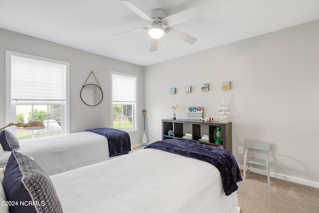 carpeted bedroom featuring multiple windows and ceiling fan