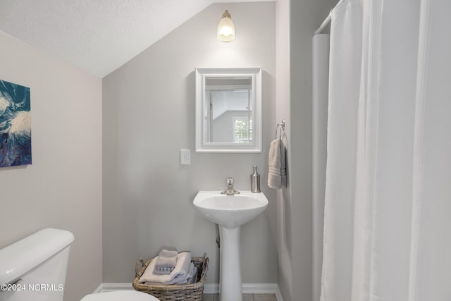 bathroom featuring lofted ceiling, a textured ceiling, and toilet