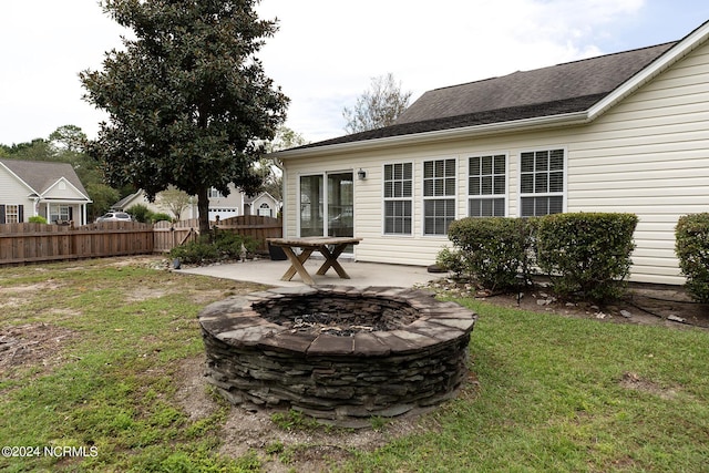 back of property featuring a yard, a patio, and an outdoor fire pit