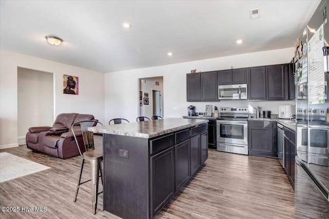 kitchen featuring appliances with stainless steel finishes, a kitchen breakfast bar, light hardwood / wood-style flooring, and a kitchen island