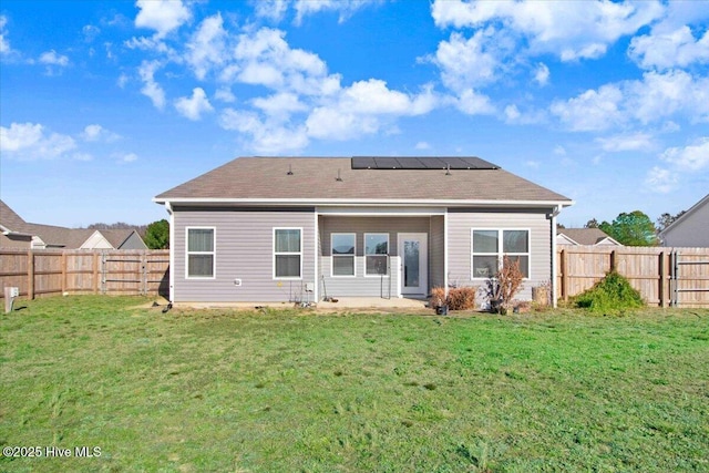 rear view of house featuring a lawn and solar panels