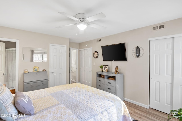 bedroom with light wood-type flooring, two closets, and ceiling fan