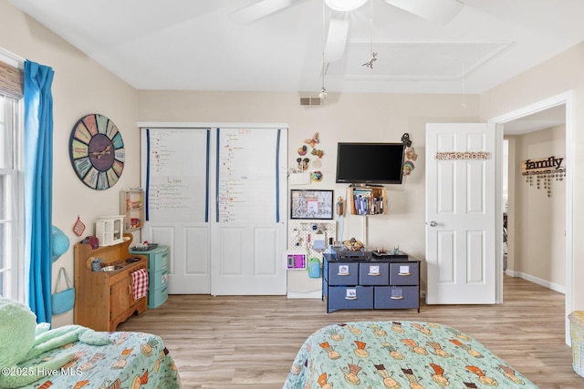 bedroom with light hardwood / wood-style flooring, ceiling fan, and a closet