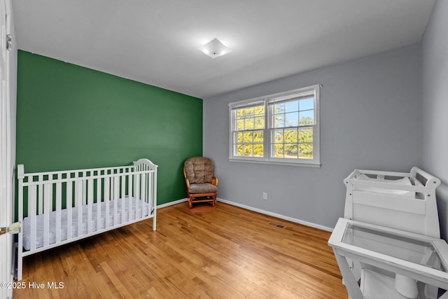 bedroom with a nursery area and light hardwood / wood-style flooring