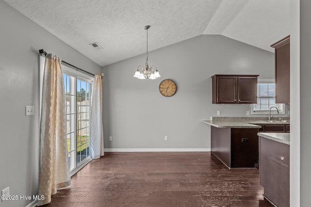 kitchen featuring dark brown cabinetry, sink, vaulted ceiling, hanging light fixtures, and dark hardwood / wood-style flooring