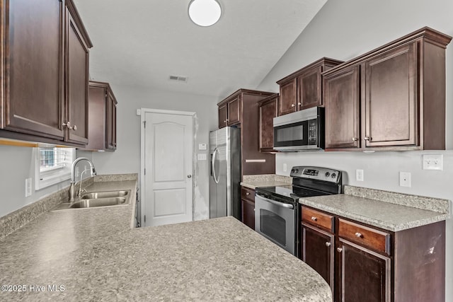 kitchen with sink, appliances with stainless steel finishes, dark brown cabinetry, a textured ceiling, and kitchen peninsula