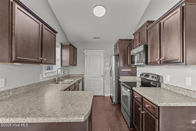 kitchen featuring appliances with stainless steel finishes, sink, dark hardwood / wood-style flooring, dark brown cabinetry, and kitchen peninsula