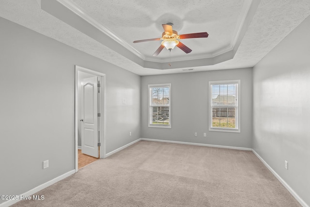 carpeted spare room with a raised ceiling, crown molding, ceiling fan, and a textured ceiling