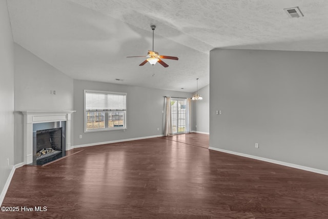 unfurnished living room featuring lofted ceiling, ceiling fan with notable chandelier, a textured ceiling, and dark hardwood / wood-style flooring