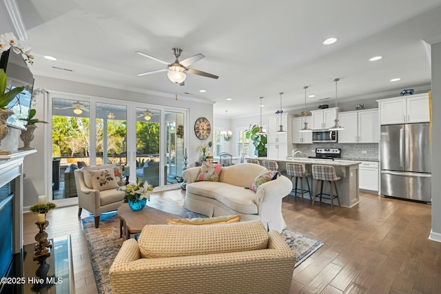 living room with ornamental molding, dark hardwood / wood-style floors, and ceiling fan