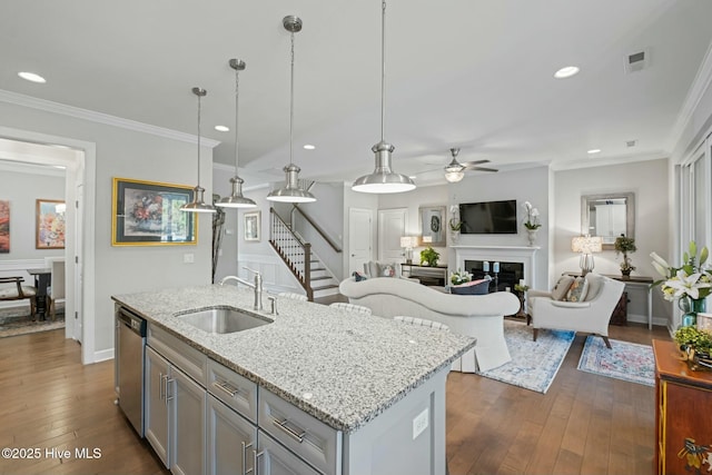 kitchen featuring sink, light stone counters, a center island with sink, stainless steel dishwasher, and pendant lighting