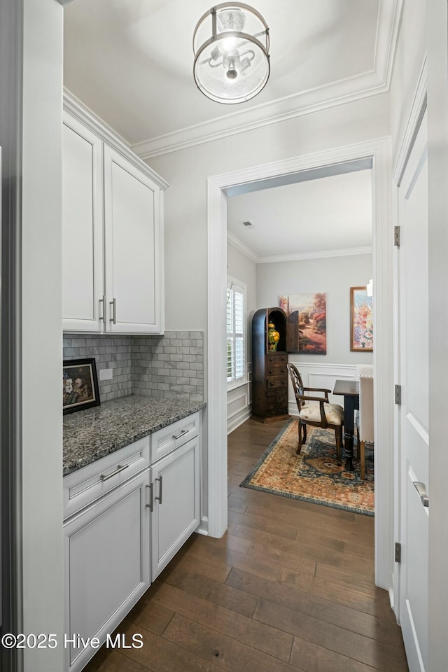 kitchen featuring tasteful backsplash, stone countertops, ornamental molding, dark hardwood / wood-style flooring, and white cabinets