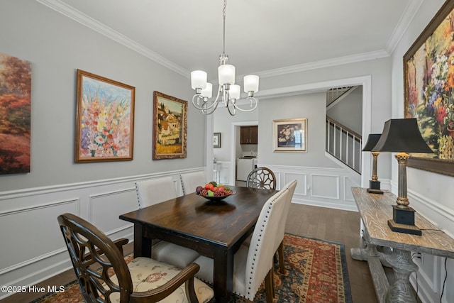 dining space featuring washing machine and clothes dryer, ornamental molding, dark hardwood / wood-style floors, and a chandelier