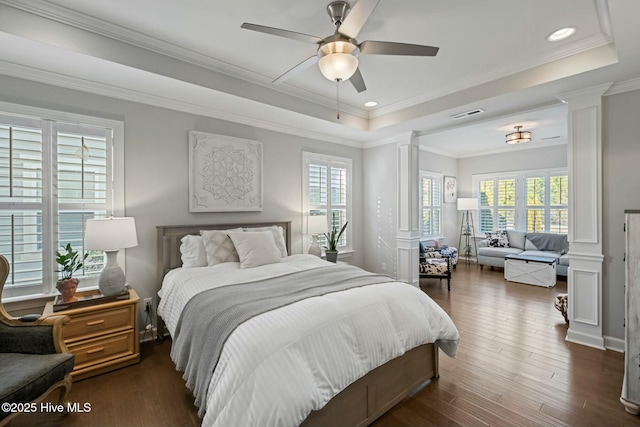 bedroom with dark hardwood / wood-style flooring, a raised ceiling, decorative columns, and multiple windows