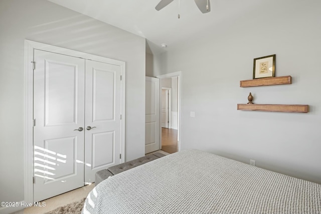 bedroom with ceiling fan, light colored carpet, and a closet