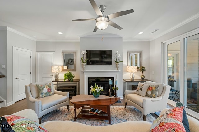 living room featuring hardwood / wood-style flooring, ceiling fan, and ornamental molding