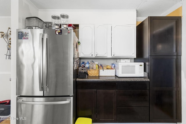 kitchen featuring a textured ceiling, white cabinetry, crown molding, and stainless steel refrigerator