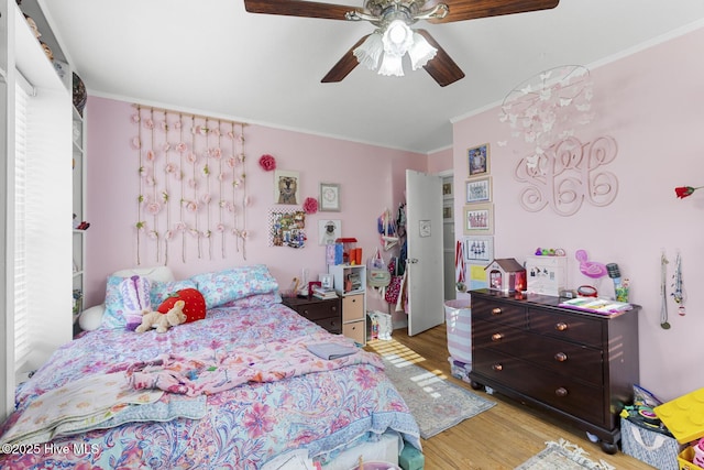 bedroom featuring ceiling fan, light hardwood / wood-style flooring, ornamental molding, and multiple windows