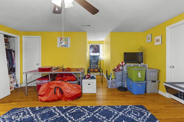 playroom with a textured ceiling, ceiling fan, and wood-type flooring