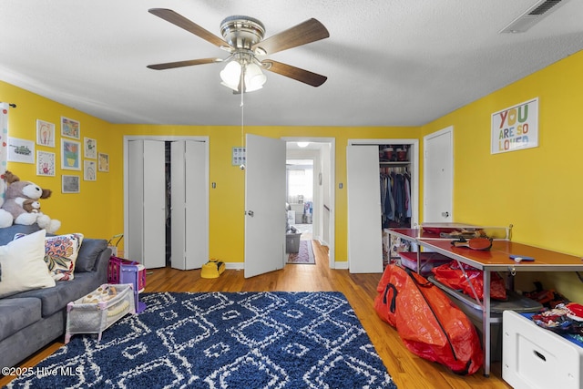 interior space with a textured ceiling, ceiling fan, and light hardwood / wood-style flooring