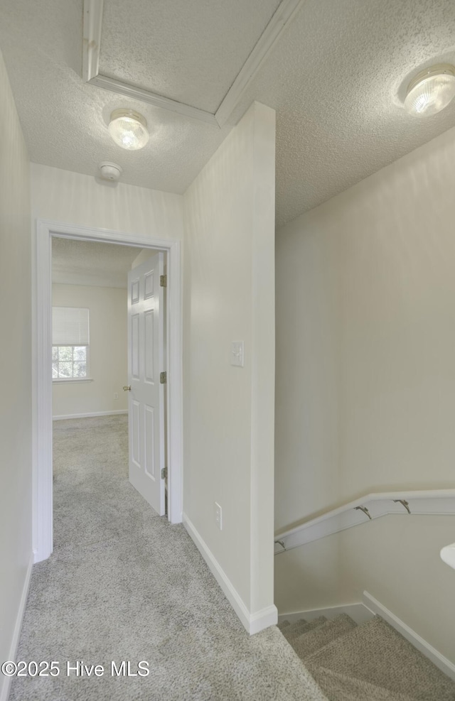 hall with a textured ceiling and light carpet