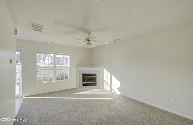 unfurnished living room with light colored carpet, ceiling fan, and a textured ceiling