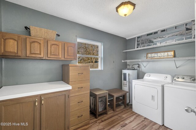 1126 Ccc Rd, Sneads Ferry, NC 28460 - clothes washing area with electric water heater, light hardwood / wood-style floors, washer and clothes dryer, a textured ceiling, and cabinets
