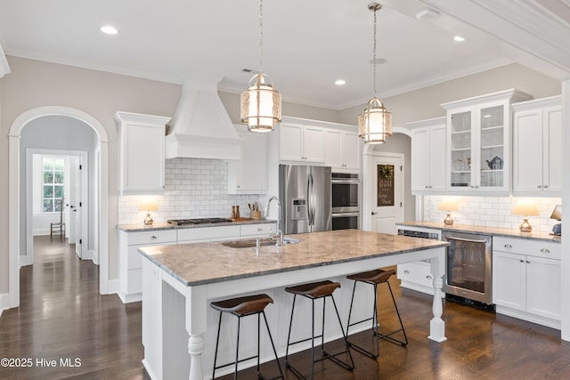 kitchen featuring appliances with stainless steel finishes, wine cooler, a kitchen island with sink, and sink