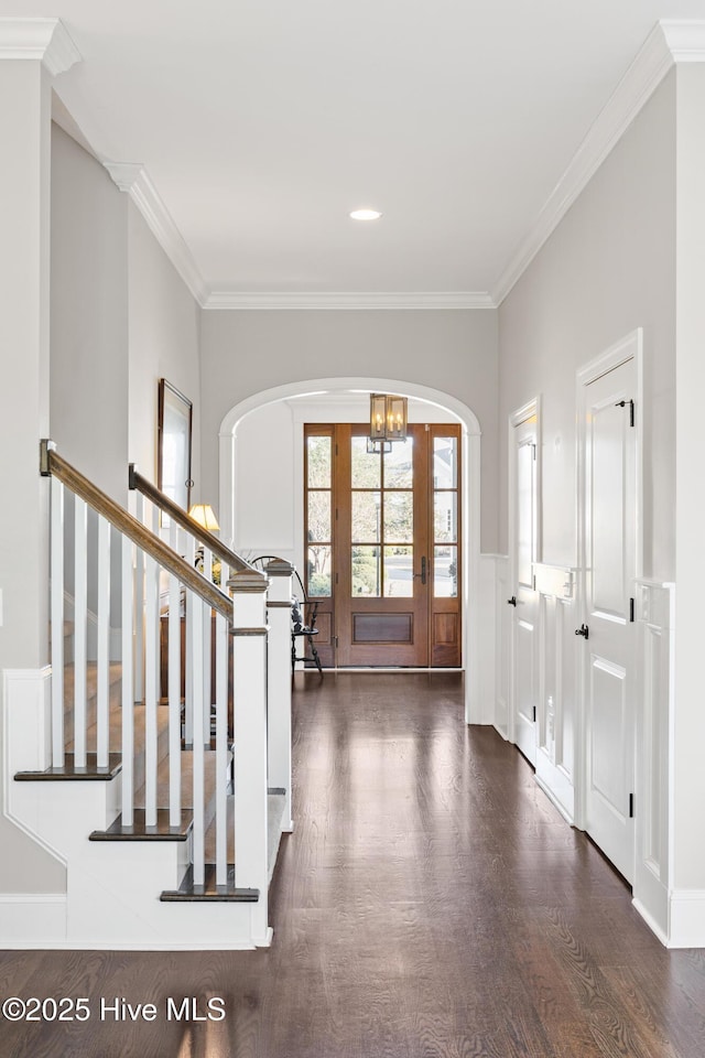 foyer entrance with an inviting chandelier, ornamental molding, and dark hardwood / wood-style flooring