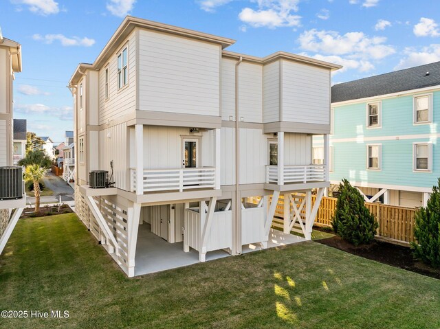 rear view of property featuring central AC unit and a lawn