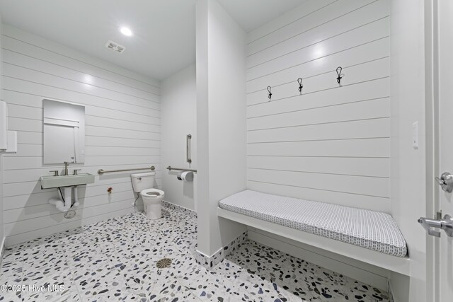 bathroom with toilet, sink, tile patterned floors, and wooden walls