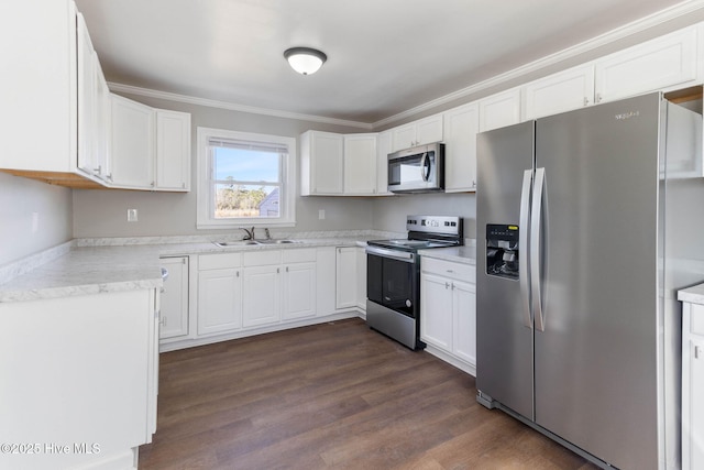 kitchen featuring appliances with stainless steel finishes, dark wood-type flooring, ornamental molding, white cabinets, and sink