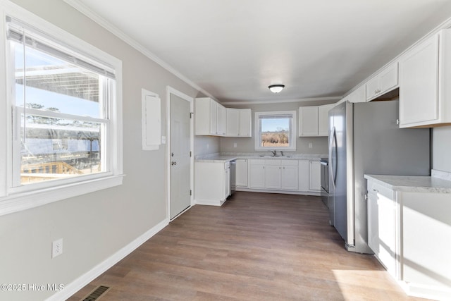 kitchen featuring white cabinets, appliances with stainless steel finishes, light hardwood / wood-style floors, sink, and crown molding