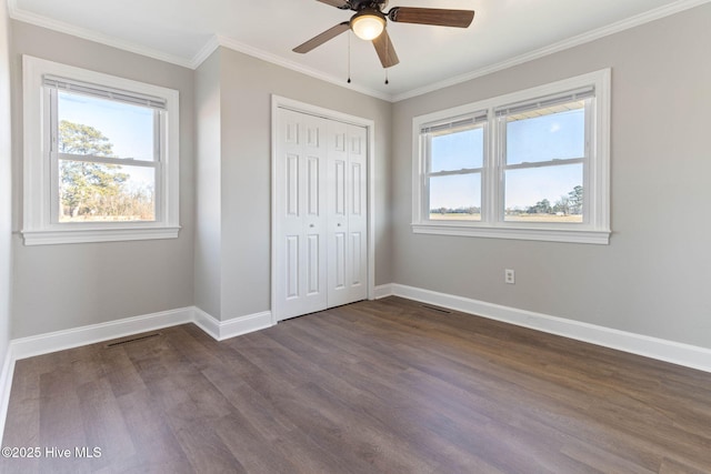 unfurnished bedroom featuring ceiling fan, a closet, dark hardwood / wood-style floors, and crown molding