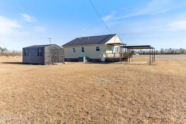 rear view of house featuring a wooden deck, a lawn, and a storage unit